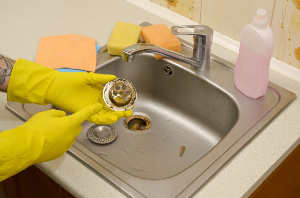 A person wearing yellow gloves is holding a glass.