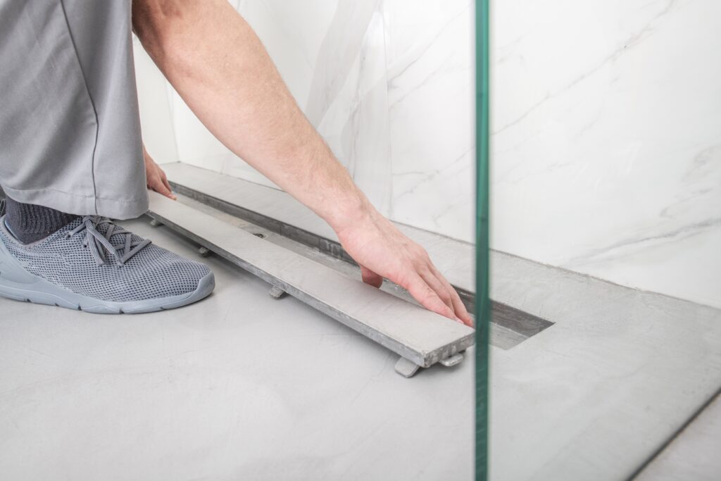 A person is using the floor tile to cut into a length.