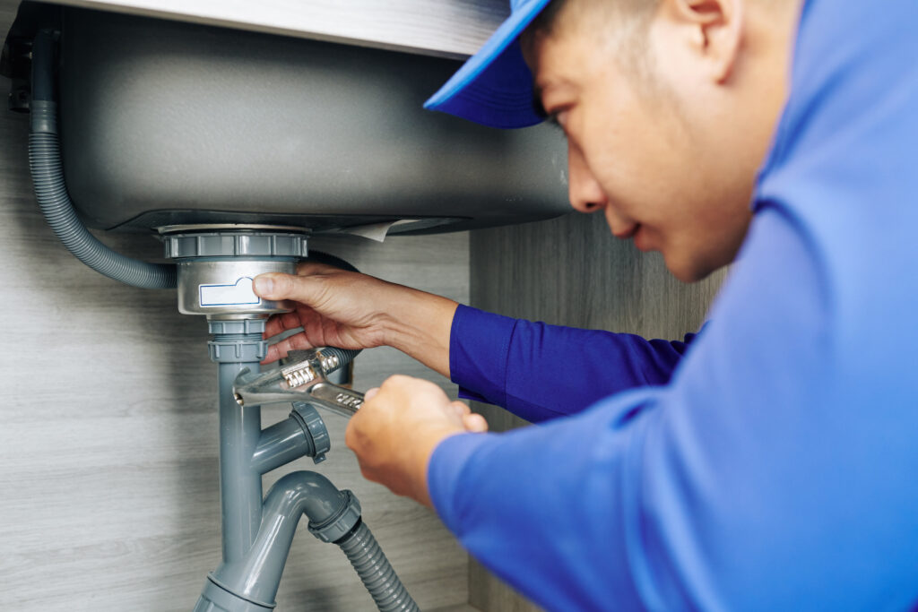 A man working on the pipes of a sink.